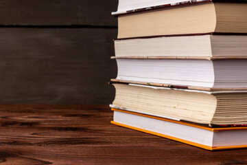 Close-up stack of books on a wooden table with space for text. Books in the library on the table. Literature about business. Novels and tales, adventures, stories. The background for design.
