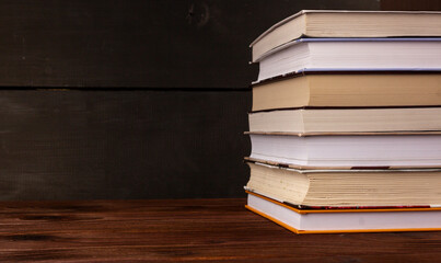 Close-up stack of books on a wooden table with space for text. Books in the library on the table. Literature about business. Novels and tales, adventures, stories. The background for design.