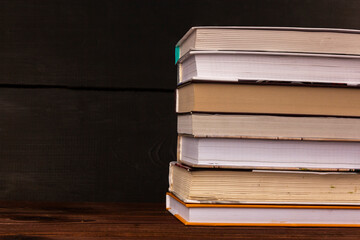 A row of books on a brown wooden surface. Selective focus. Books stacked against a dark background. Books on shelf in library, home, school or office interior. Novels, fairy tales, stories.