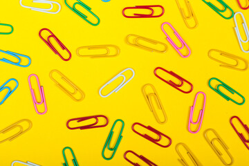 Back to school shopping concept. School office supplies paper clips on yellow background. Flat lay top view, copy space.