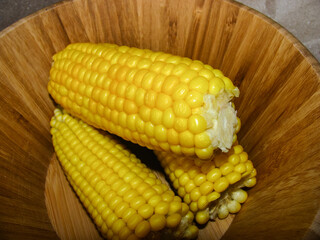 Cooked juicy corn halves in a bamboo bowl
