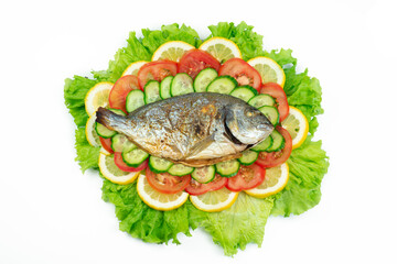 Ggrilled dorado fish with vegetables: salad, tomatoes, cucumber, green pepper and lemon