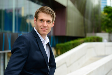 Fototapeta premium Young handsome businessman in the city streets outdoors
