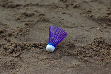 blue badminton shuttlecock on trampled sand