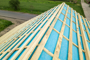 Brick house with wooden roof frame under construction. © bilanol