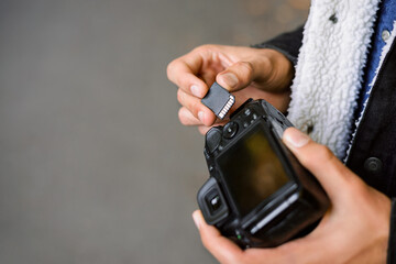 Male photographer inserting SD memory card into dslr camera