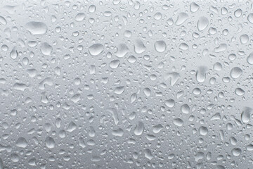Drops of rain on the grey metallic surface of a car. Background with rain drops