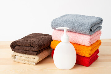 Bottle with shower gel with a stack of towels on wooden table
