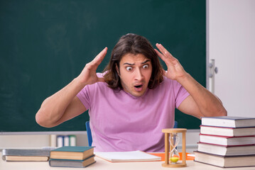 Young male student in the classroom at time management concept