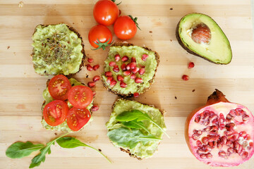 Four kinds of guacamole sandwiches, top view on a bamboo wooden board, top view