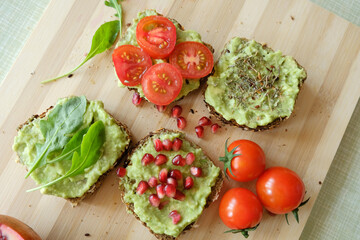 Various kinds of guacamole sandwiches, top view on a bamboo wooden board, top view