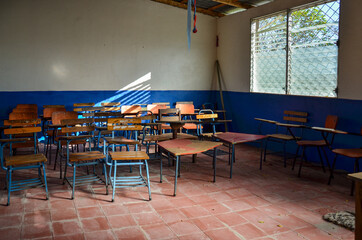 Inside a classroom with chairs and desks in a public school class in Nicaragua. Room and equipment in poor condition. Wood chairs and tables no students. Concept for education in developing countries