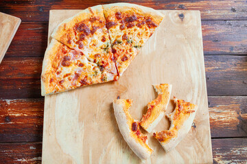 Pizza on a wooden tray. Dry crusts of the edge of the pizza bitten lie nearby. The man didn't...