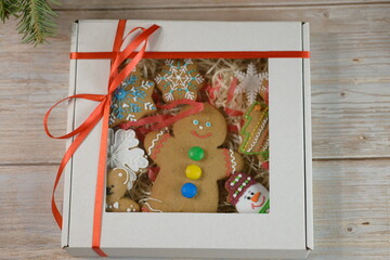 Gingerbread cookie in a gift box lies near the Christmas tree. Christmas and New Year composition with cookies, Christmas tree and mandarin citrus