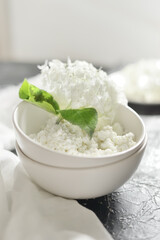 white fresh rustic cottage cheese decorated with a flower sprig in a white plate on a white background.  protein healthy diet eco product