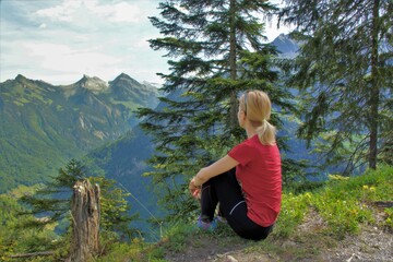 a girl sitting on the edge of a mountai