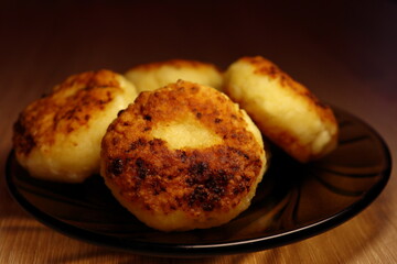 Cottage cheese pancakes (syrniki) on the black plate. Close up view. Food photography.