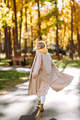 Portrait of a beautiful happy woman with a smile in autumn park. Young girl enjoying rest and freedom. Relaxation and lifestyle concept.