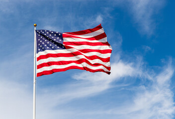 Bright American flag waving in the wind, with vibrant red white and blue colors lit by the sun,...
