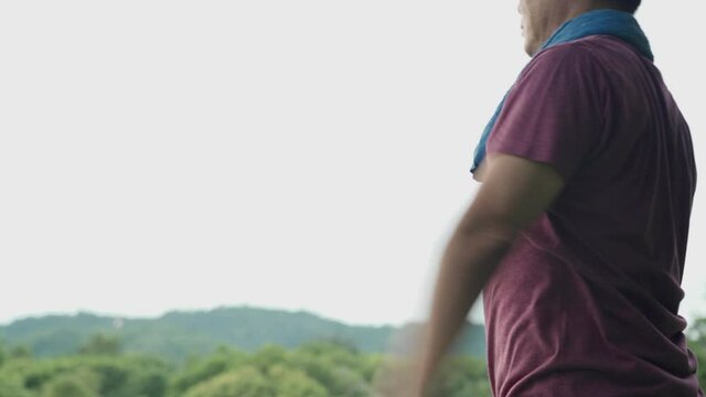 Asian man doing standing arms swing exercise to warm up at the park, new life adventure arms full stretch, health care, mid body section, easy simple basic exercise for beginner, diet losing weight