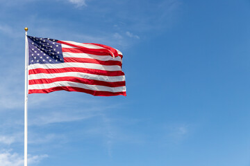 Beautiful American flag waving in the wind, with vibrant red white and blue colors against blue...