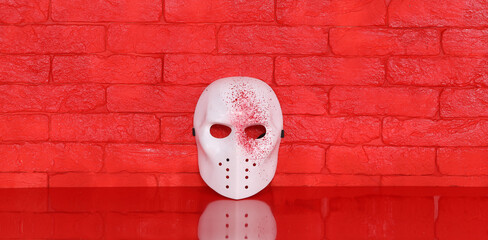 white killer mask on red table, red brick wall background