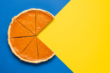 Pumpkin pie home-baked, above view. Sliced pie isolated on a colorful background © YesPhotographers