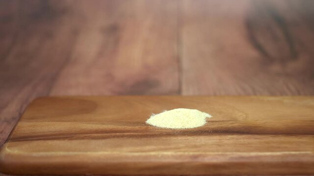 A pile of garlic powder sugar on a wooden board on brown table in 4K.