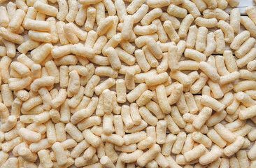 Background of beige corn sticks. A quick snack concept.