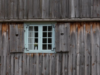 Obraz na płótnie Canvas Window with white frames and wooden shutters with a heart shape cutout, Kashubian Ethnographic Park, Wdzydze Kiszewskie, Poland