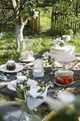 Details of a rustic wedding table with cake, strawberries, flowers and sweet elements