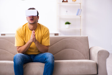 Young man with virtual reality glasses at home