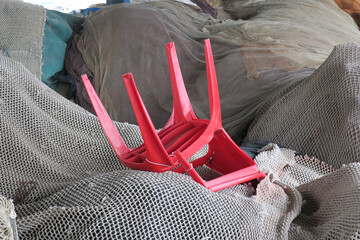 red plastic chair laying on a heap of fishing nets