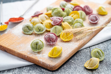 Fototapeta na wymiar Raw home-made multi-colored dumplings or ravioli on a cutting Board. Recipe dishes for children