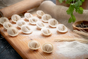 Raw homemade dumplings or ravioli on a chopping wooden Board. Recipe for cooking a Russian dish