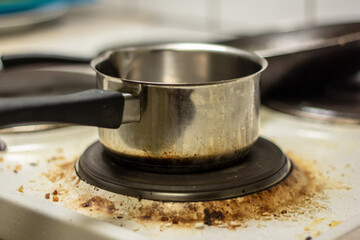 A saucepan and a pan on the dirty white stove.