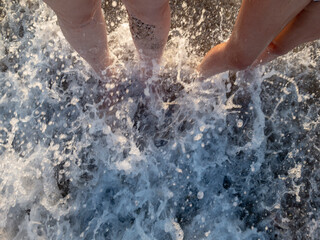 two ladies are standing in the waves by the sea