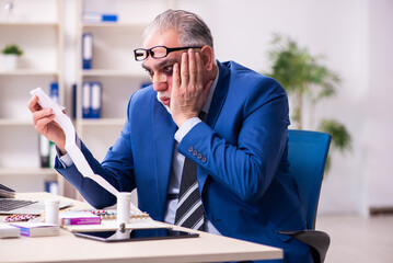 Old face injured employee sitting in the office