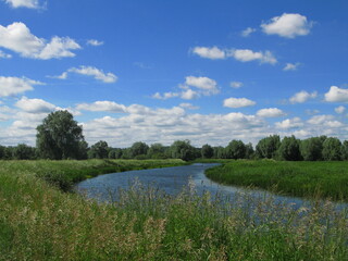 Rural landscape with Motlawa river in Olszynka district at the far end of Gdansk - blue sky with some clouds, river and green grass