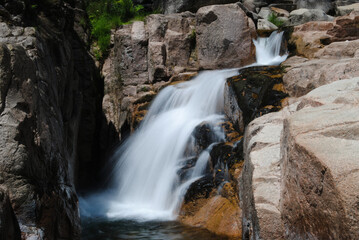 Fototapeta na wymiar Cascata numa montanha com água a correr a alta velocidade por entre as rochas, montanha