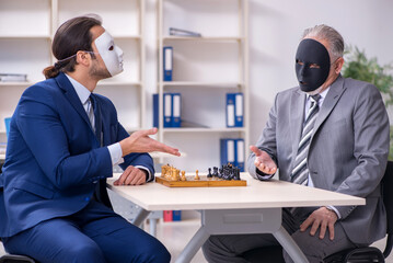 Two businessmen playing chess wearing masks