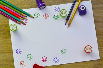 Colored pencils and stamps on white paper, work desk, back to school