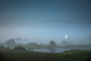 Pre-dawn fog with a low moon over the river floodplain.