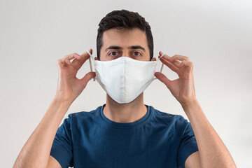 Young man putting on a mask to cover his mouth and nose to have protection from the coronavirus pandemic
