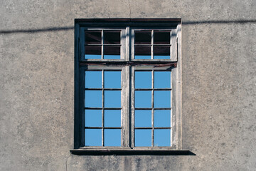 isolated outdoor view of old wooden closed window in abandoned buiding, with sky behind
