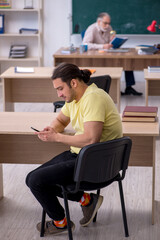 Old teacher and young male student in the classroom