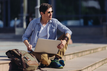 Hnadsome confident successful modern male entrepreneur holding laptop and looking away