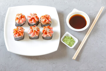 Japanese sushi with soy sauce and wasabi with chopsticks on a grey concrete background. Top view
