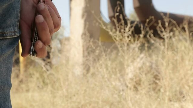 A man takes the pocket knife out of his jeans and secretly opens it, standing outdoors, also in his car