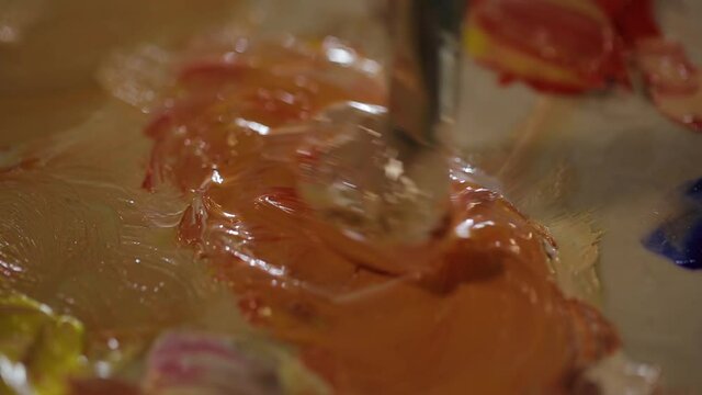 The artist mixes paints with a brush. Close-up of a brush. Mixing yellow, white and red. Part2